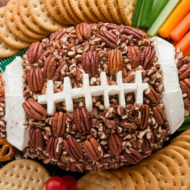 Cheeseball shaped like a football surrounded by crackers and veggies