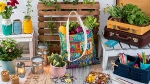 A colorful tote bag filled with fresh vegetables sits among potted plants, herbs, suitcases, jars, a lantern, and gardening tools—showcasing upcycling projects and creating a vibrant, cozy indoor gardening scene.