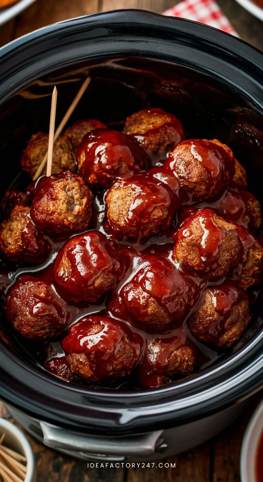 Juicy BBQ meatballs glistening with sauce, served in a crockpot with a small bowl of toothpicks on the side.