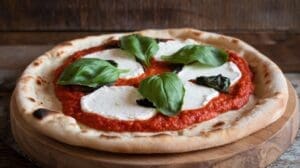 A Margherita pizza on a wooden board topped with tomato sauce, mozzarella cheese, and fresh basil leaves, with a rustic wooden background.