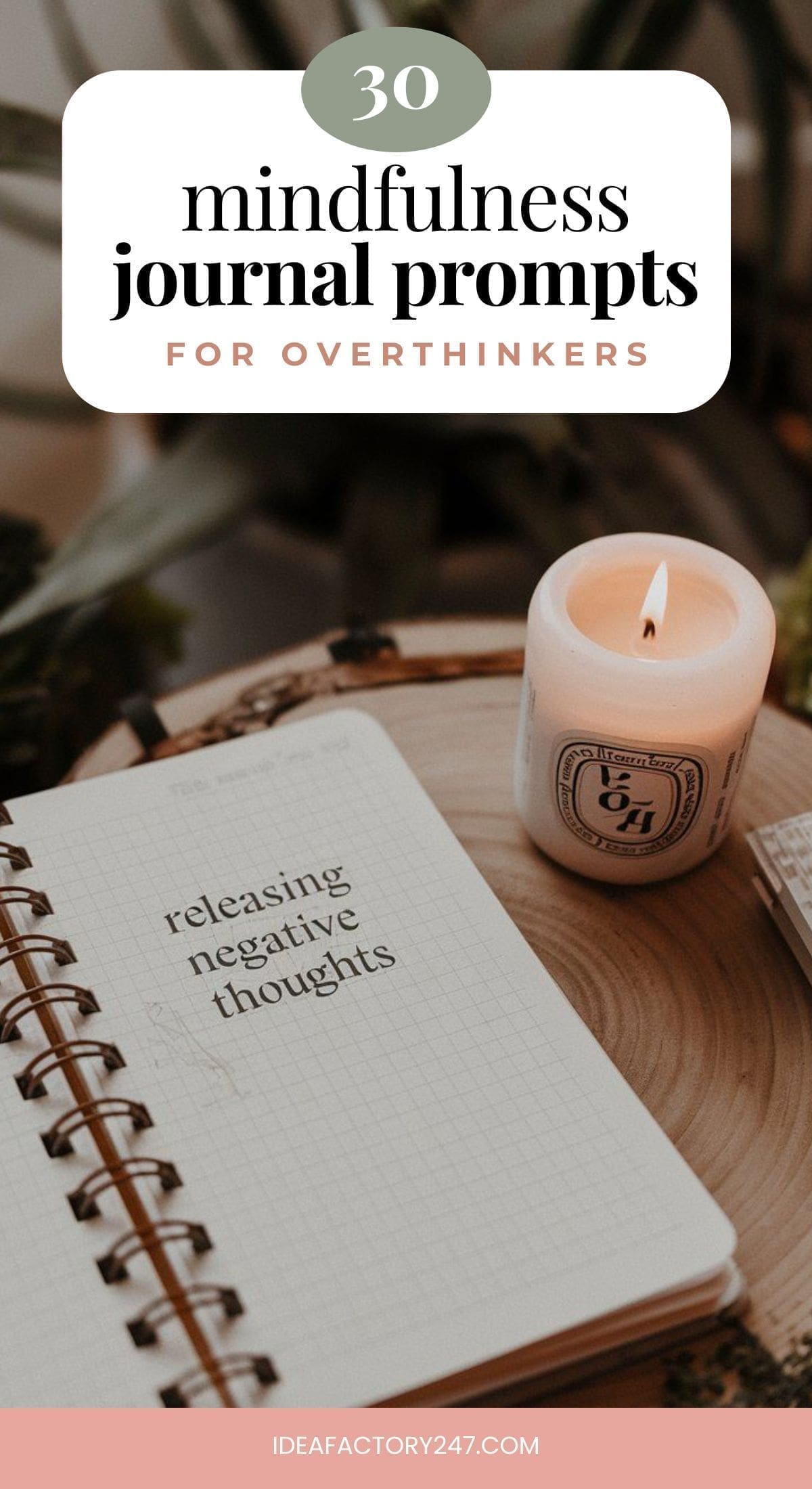 An open notebook on a wooden table displays the words releasing negative thoughts. A lit candle and potted plant sit in the background, creating a serene ambiance. This image introduces 30 mindfulness journal prompts for overthinkers.