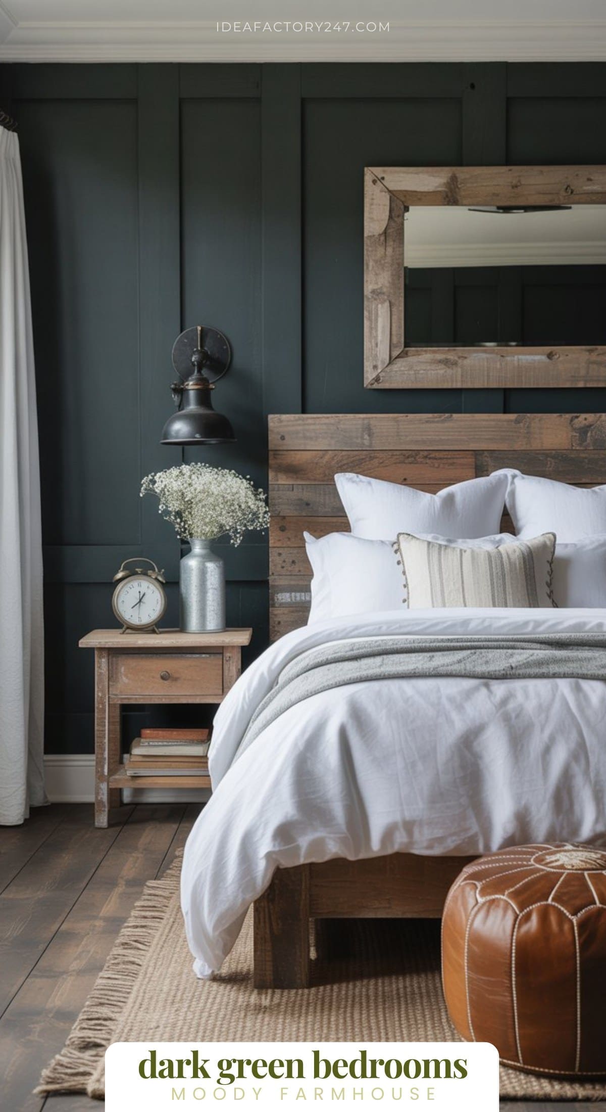 Obsessed with dark green decor? We are too! This farmhouse style bedroom is part of our moody deep green bedrooms collection. A cozy farmhouse bedroom with dark green paneled walls, rustic wood bed and nightstand, white bedding, a large wood-framed mirror, vintage clock, black sconce, flowers in a vase, and a brown leather pouf.
