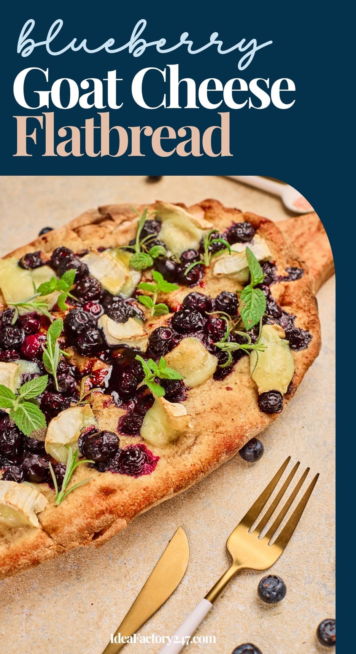 A blueberry goat cheese flatbread topped with fresh mint leaves, served on a wooden board beside a gold fork and knife on a beige surface. Blueberries are scattered nearby for decoration.