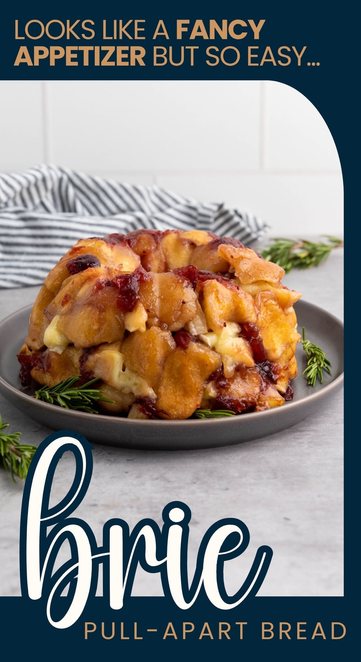 A golden, gooey Brie Pull-Apart Bread filled with melted brie and fruit preserves sits on a gray plate, garnished with rosemary. Text above reads, Looks like a fancy appetizer but so easy... brie pull-apart bread.