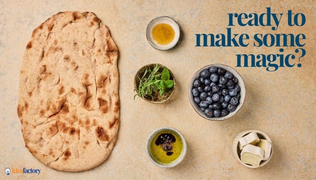 Flatbread, small bowls of honey, fresh herbs, blueberries, olive oil with balsamic vinegar, and pieces of cheese are arranged on a beige surface. Text reads, “ready to make some magic?” in blue.