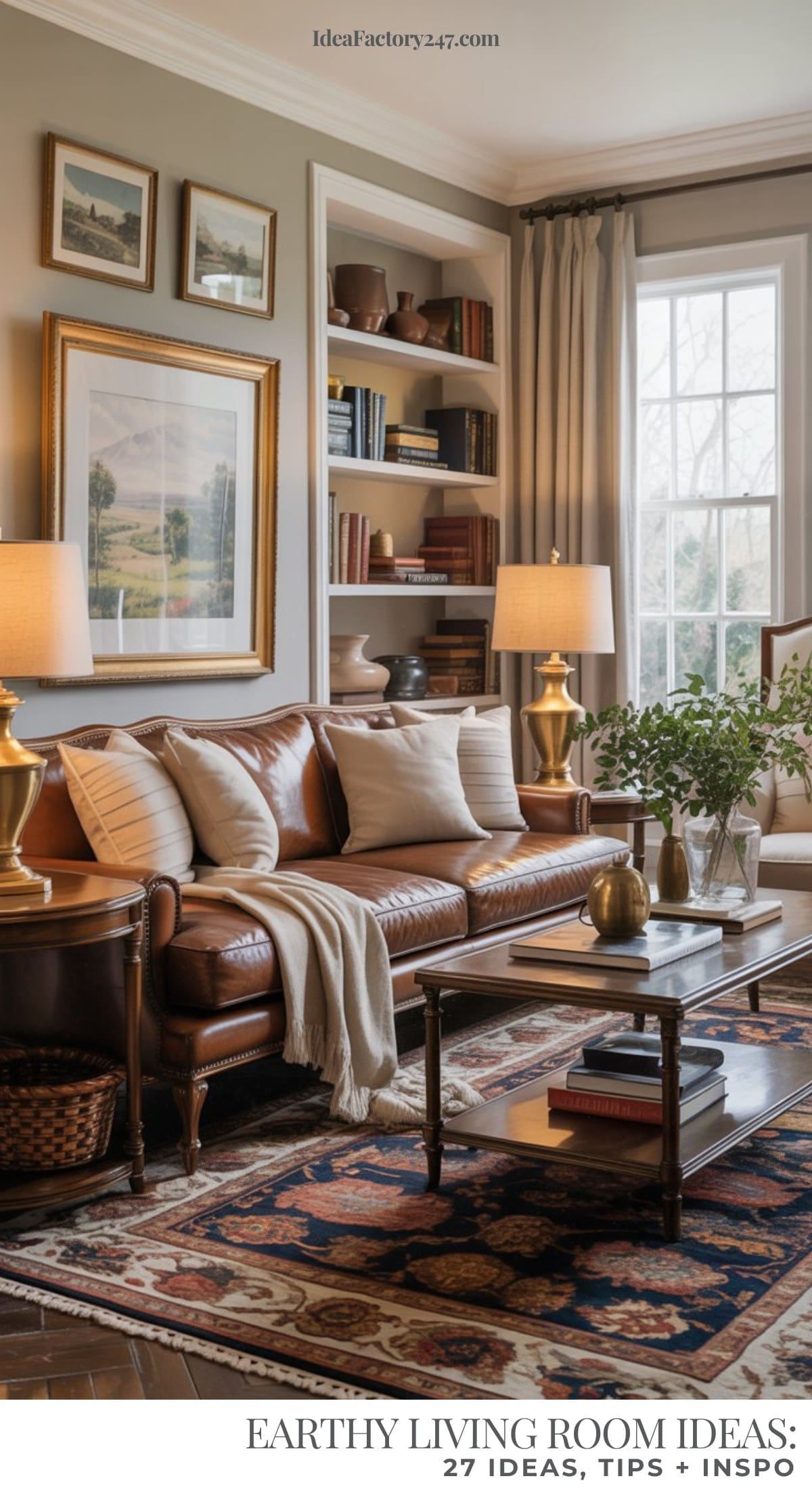 An earthy living room featuring a brown leather sofa, beige pillows, gold lamps, a patterned rug, framed art, built-in bookshelves, and a large window letting in natural light. Greenery adorns the coffee table for a fresh touch.