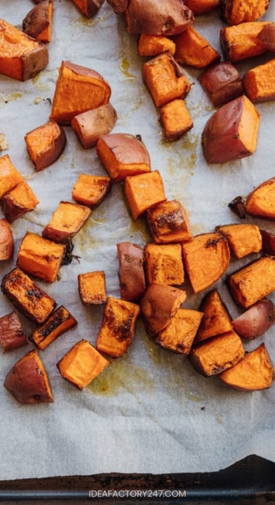 Cubed sweet potatoes with skins on, tossed with cinnamon, roasted and slightly browned, spread on a baking sheet lined with parchment paper.