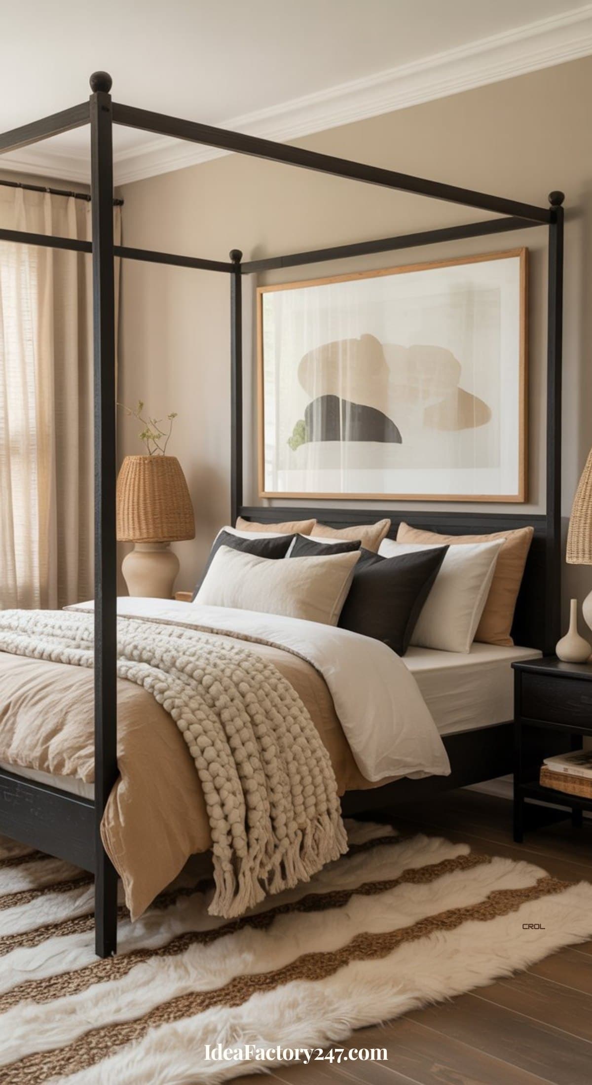 A cozy bedroom with a black canopy bed, neutral bedding, textured throw blanket, striped rug, bedside tables with woven lamps, and abstract wall art above the bed. Sunlight streams in through beige curtains.