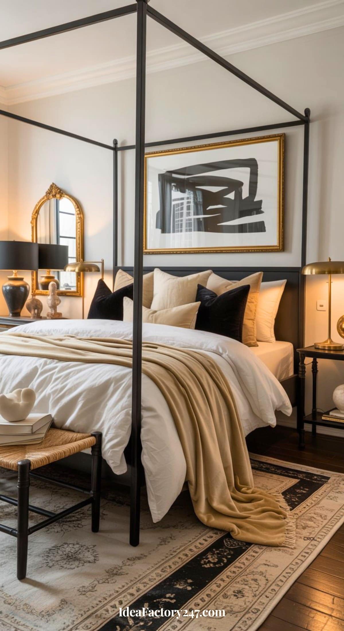 A stylish bedroom with a black four-poster bed, white bedding, beige throw, black and beige pillows, a patterned rug, a bench, modern art, and gold-accented lamps and mirrors on each side.