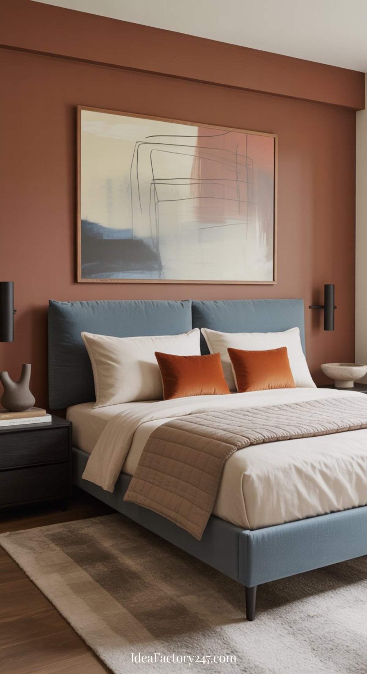 A modern blue and terracotta bedroom with a blue upholstered bed, beige bedding, rust accent pillows, and abstract wall art above the headboard. Minimalist decor and soft lighting complete the inviting look.
