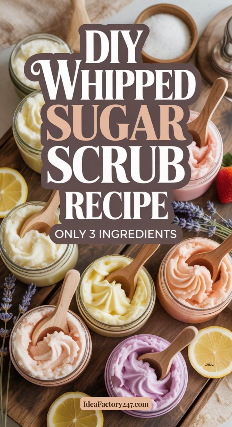 Four jars of whipped sugar scrub with wooden spoons rest on a wooden surface, surrounded by lemon slices, lavender, and a strawberry. Text reads: “DIY Whipped Sugar Scrub Recipe, Only 3 Ingredients.”.