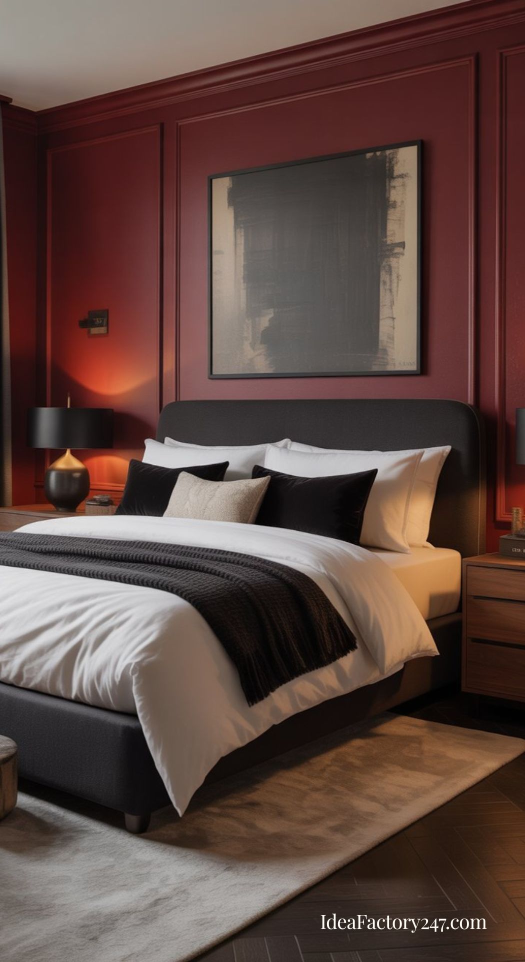 A modern bedroom with deep red walls, a dark upholstered bed with white and black bedding, two bedside tables with lamps, and abstract artwork hanging above the bed. A cream rug lies beneath the bed.