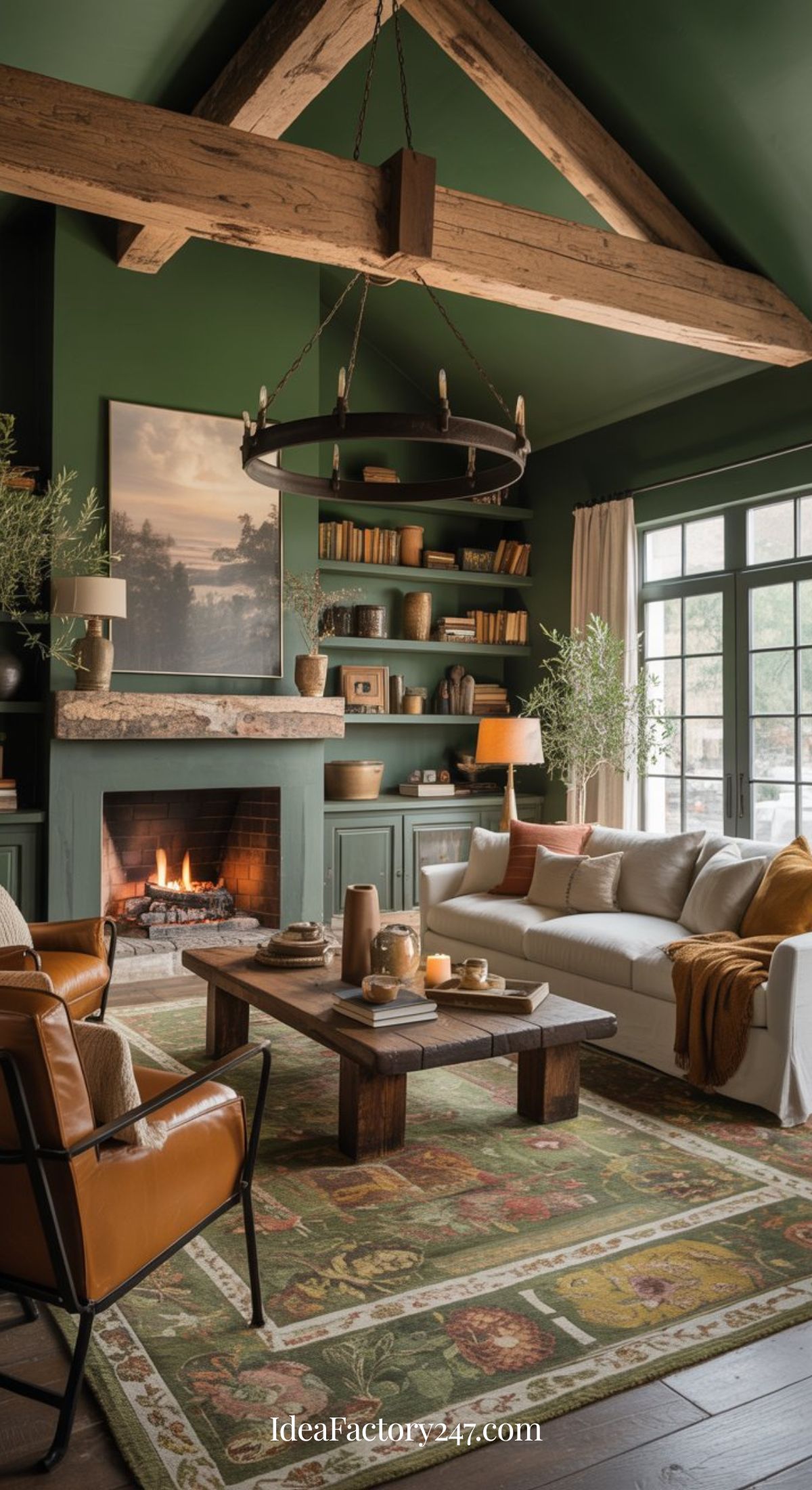 Cozy living room with green walls, exposed wooden beams, a lit fireplace, shelves with books and decor, a white sofa, leather chairs, and a rustic wooden coffee table on a patterned rug. Large windows let in natural light.