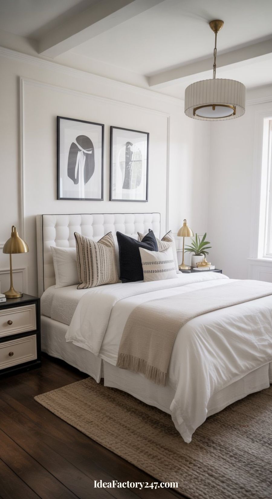 A modern, bright bedroom with a white bed, beige and black accent pillows, gold lamps on nightstands, framed monochrome art above the headboard, and natural light from a large window.