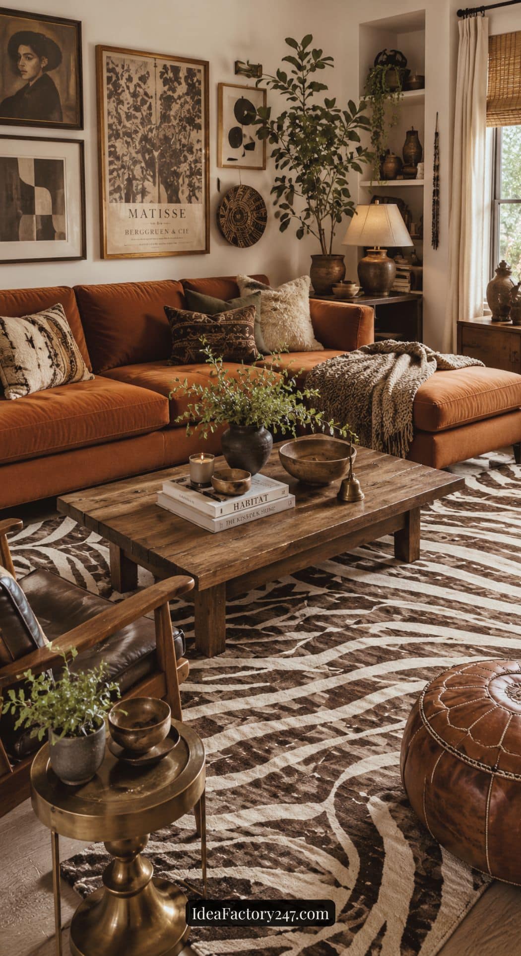 A cozy living room with a rust-colored sofa, animal print rug, wooden coffee table with books and plants, leather pouf, and eclectic wall art. Warm, earthy tones and natural textures create a welcoming atmosphere.