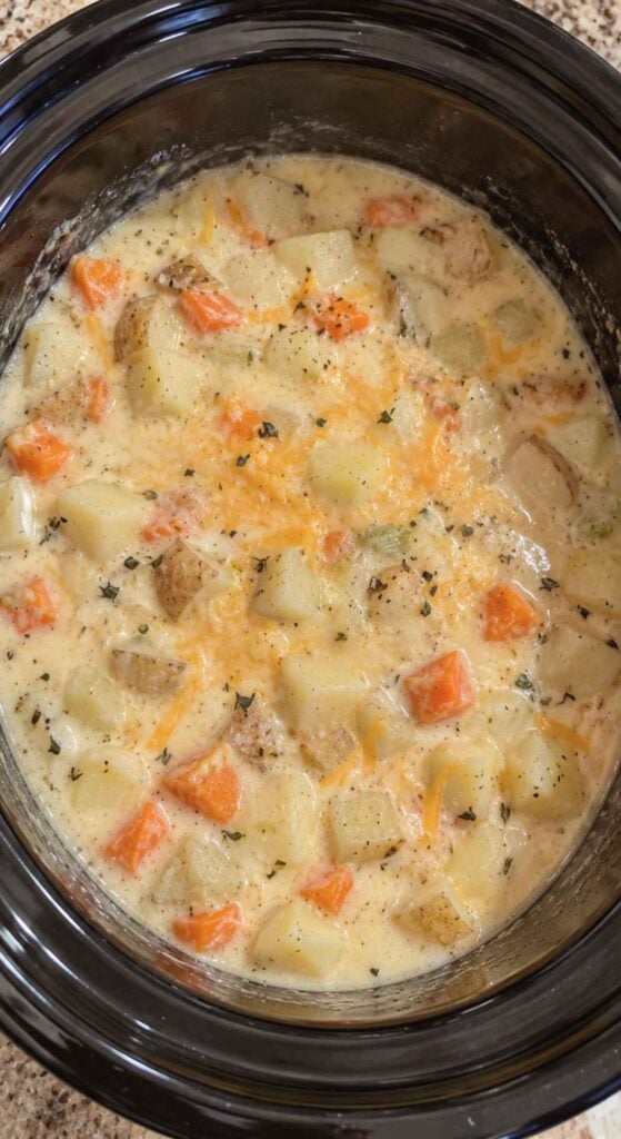 Creamy potato soup with carrots and shredded cheese in a slow cooker, a perfect choice for healthy crockpot recipes.