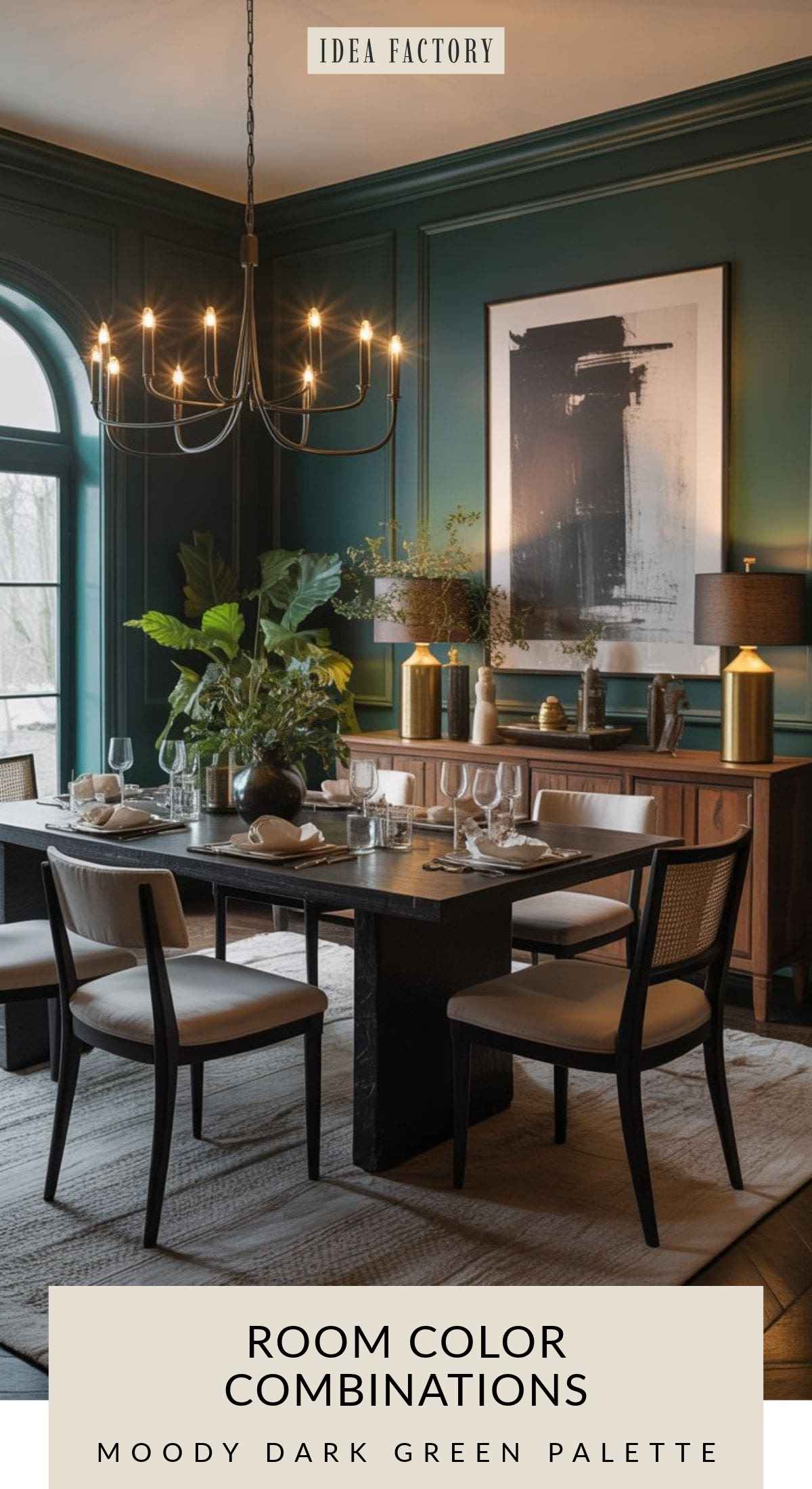 Dining room with dark green paneled walls, a black wooden table, and chairs with light upholstery, featuring a black chandelier and a large abstract print above a sideboard.
